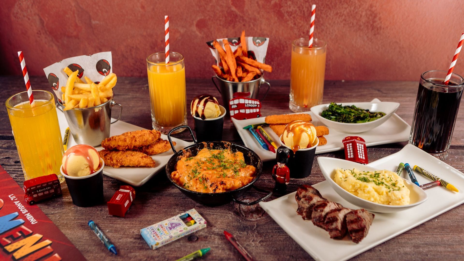 A table of food including fries, chicken tenders, drinks, and macaroni and cheese.