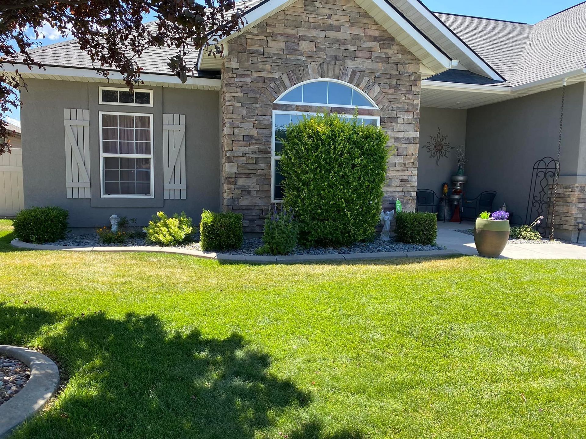Front exterior of a house with stone accents, a well-manicured lawn, and landscaping.