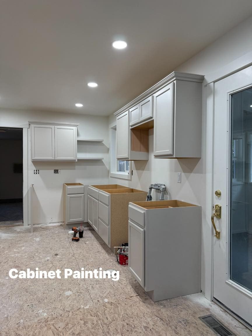 Kitchen cabinets in various stages of installation and painting, gray cabinets with exposed wood, indoor.