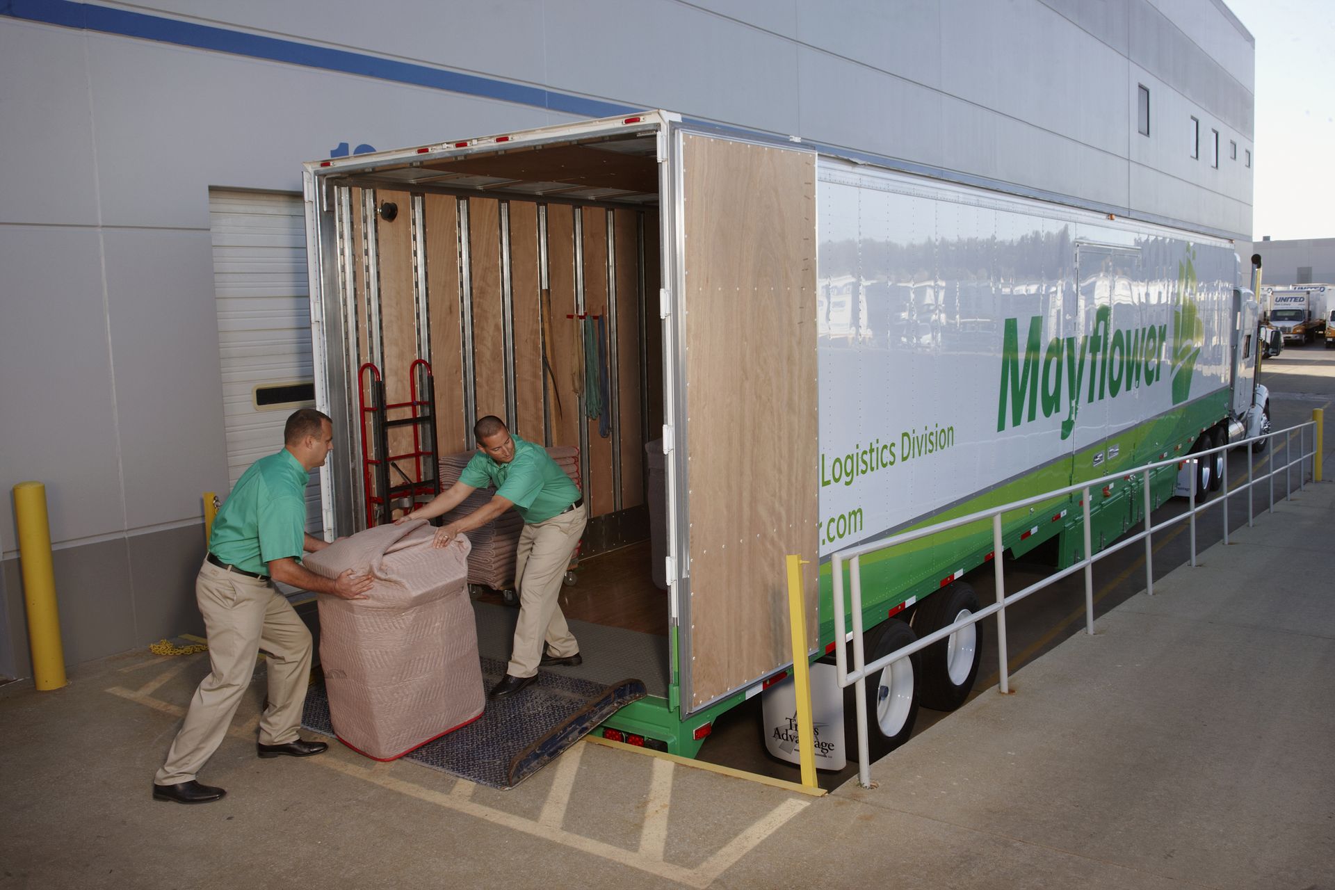 Two men are loading a large box into a moving truck.