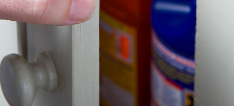 A person is holding a door handle next to a bottle of glue.