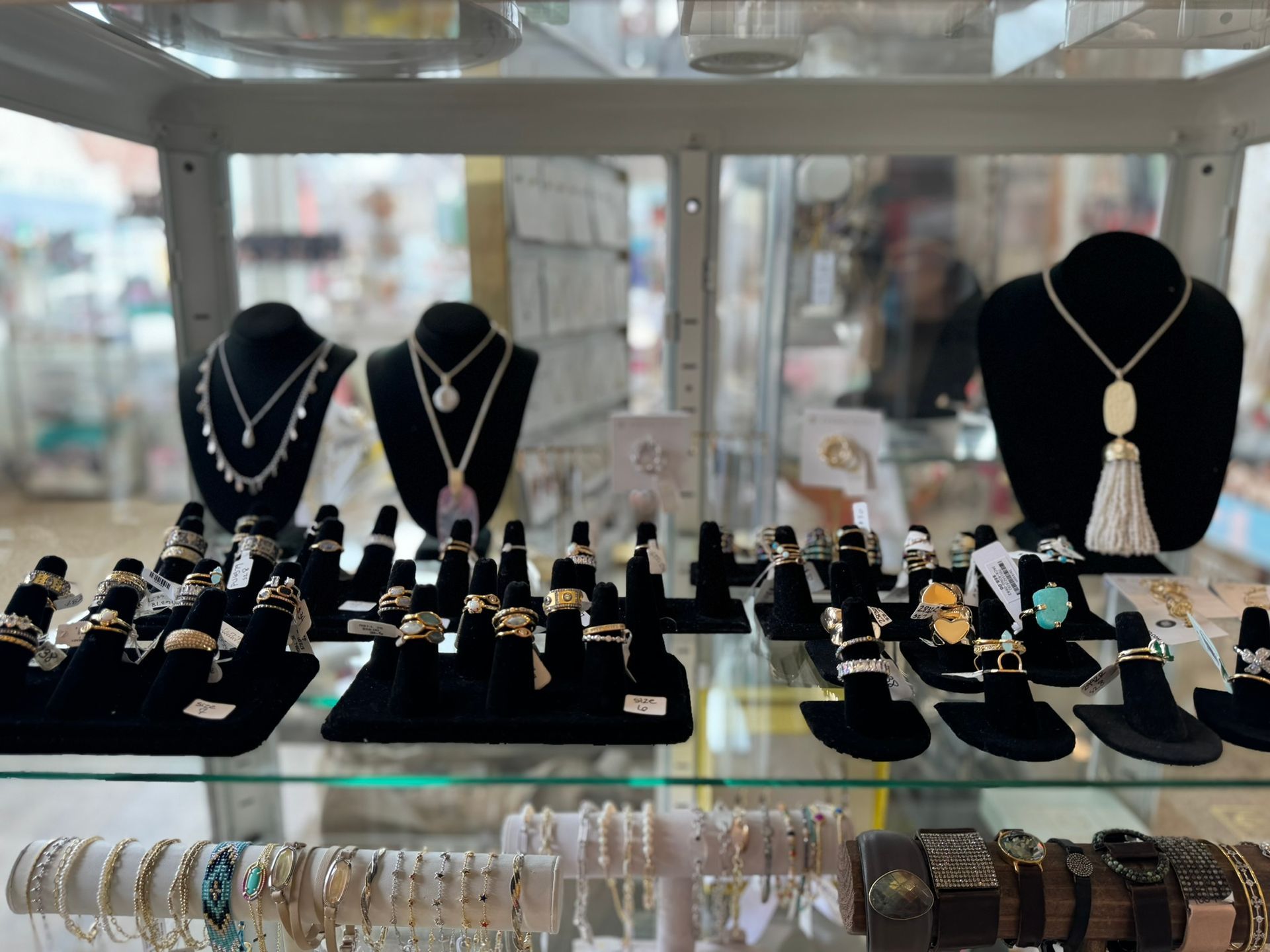 A display case filled with necklaces , rings , and bracelets on mannequins.