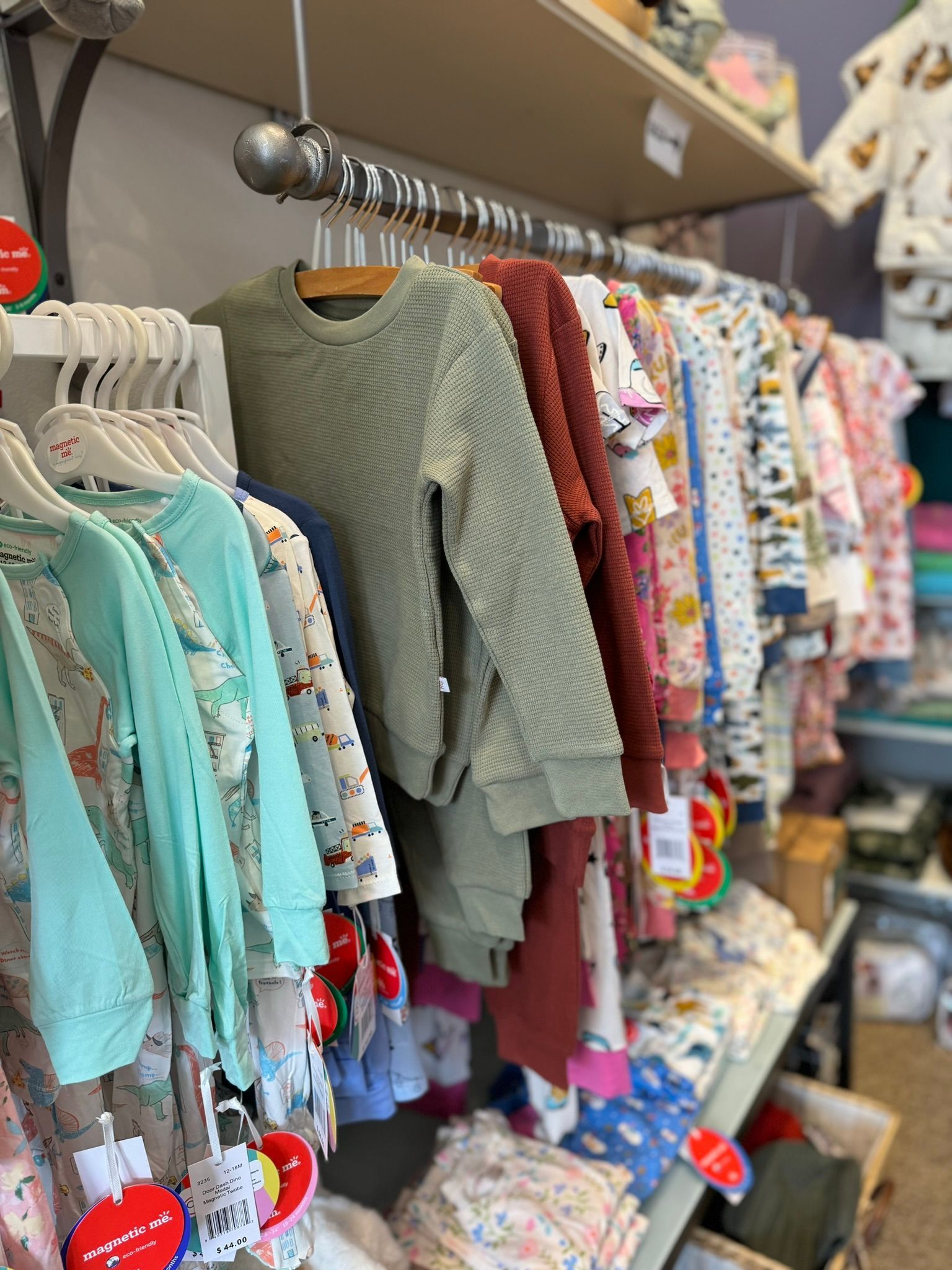 A row of baby clothes hanging on a rack in a store.