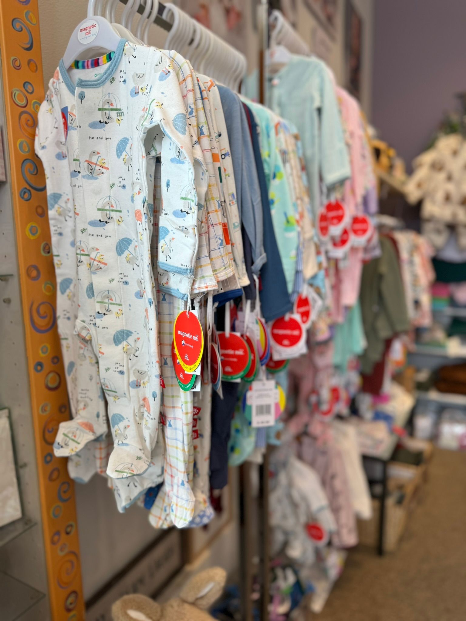 A row of baby clothes hanging on a rack in a store.