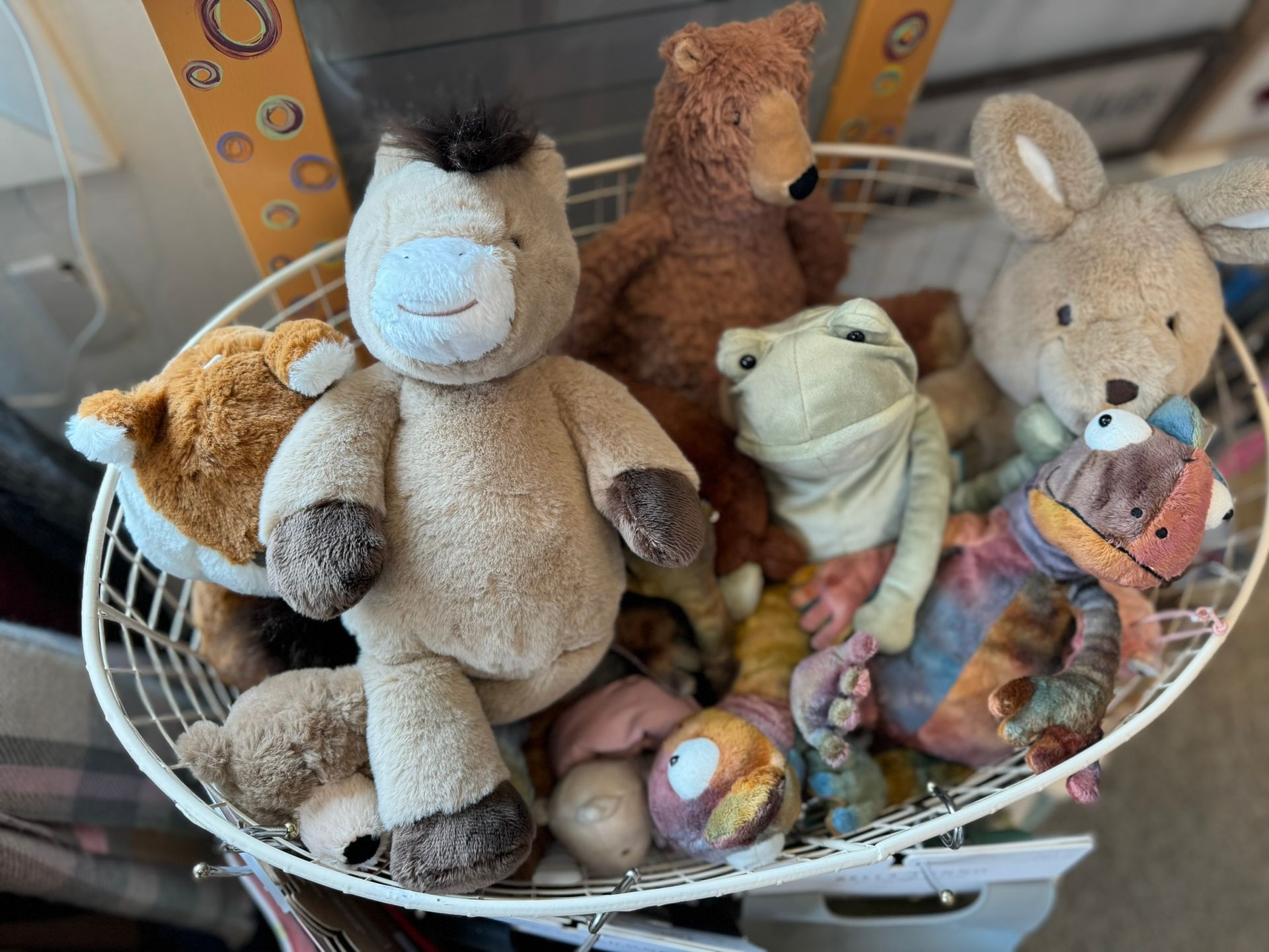 A basket filled with stuffed animals including a horse and a frog