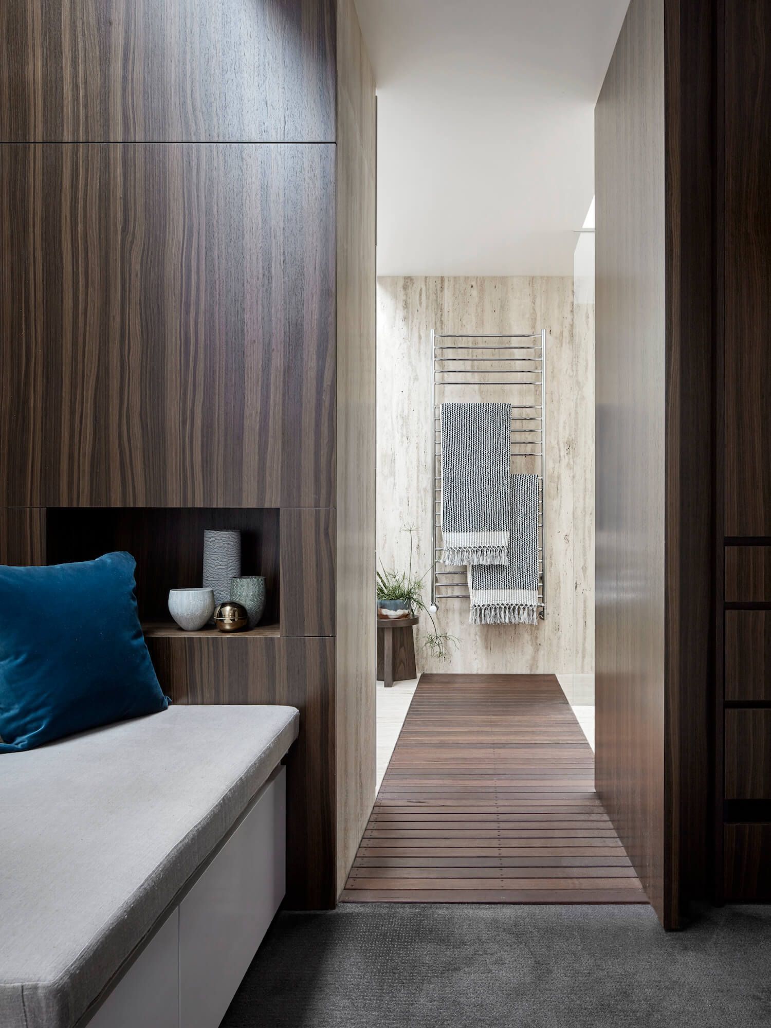 Dark wood-paneled hallway with built-in bench, leading to a bathroom with towel rack.