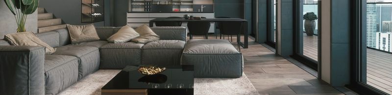 Modern living room with gray sofa, coffee table, and large windows overlooking a balcony.