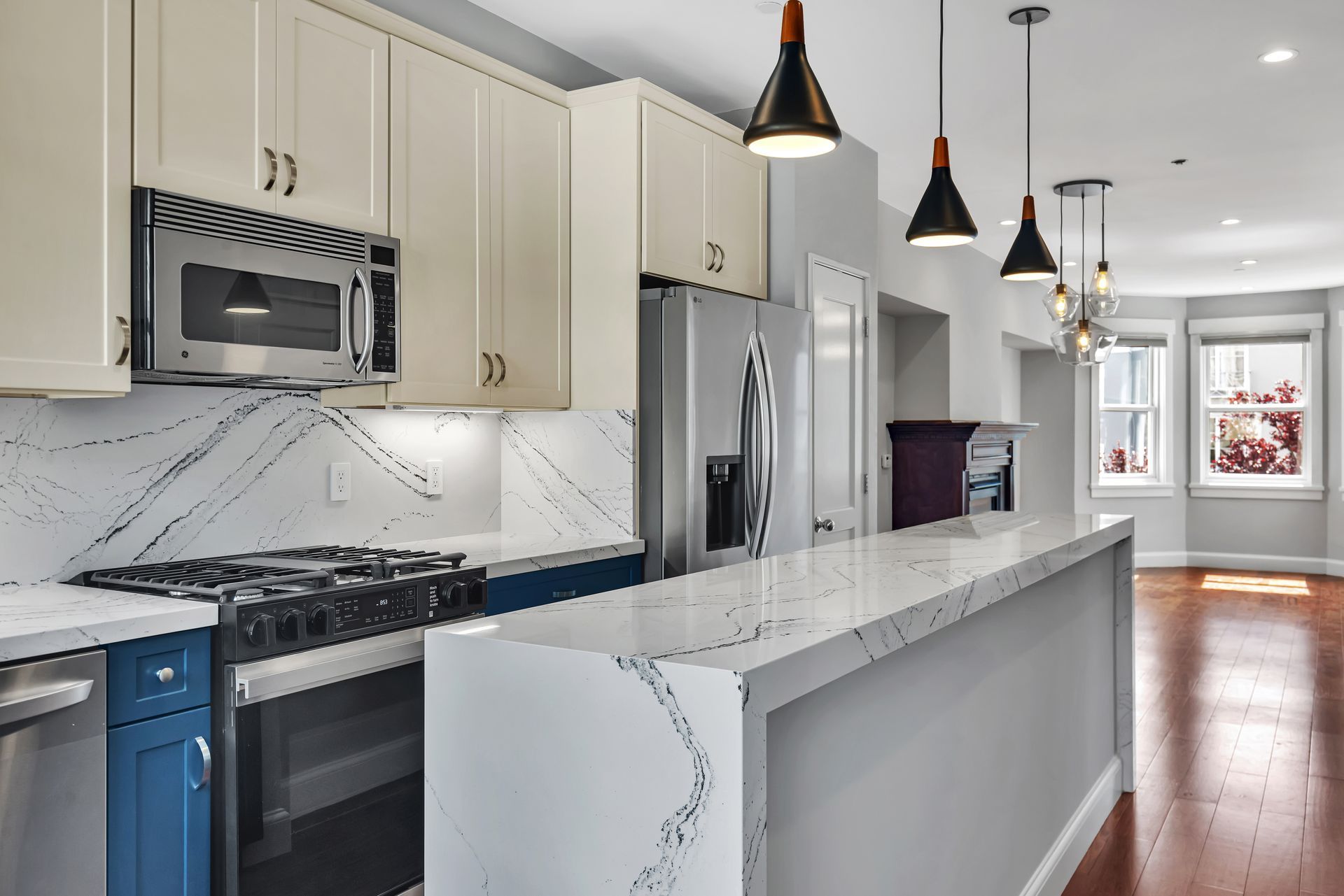 Modern kitchen with white and blue cabinets, stainless steel appliances, and quartz countertops.