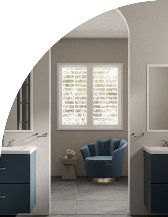 Bathroom with blue vanities, armchair, and window with shutters.