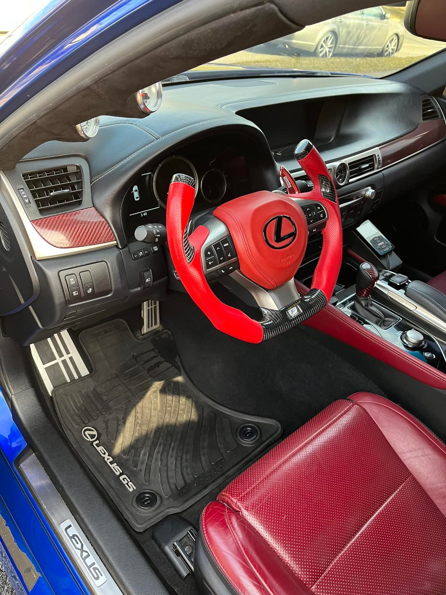 Blue car interior with red accents.  Red steering wheel, seats, and dashboard details. Lexus logo and floor mats.