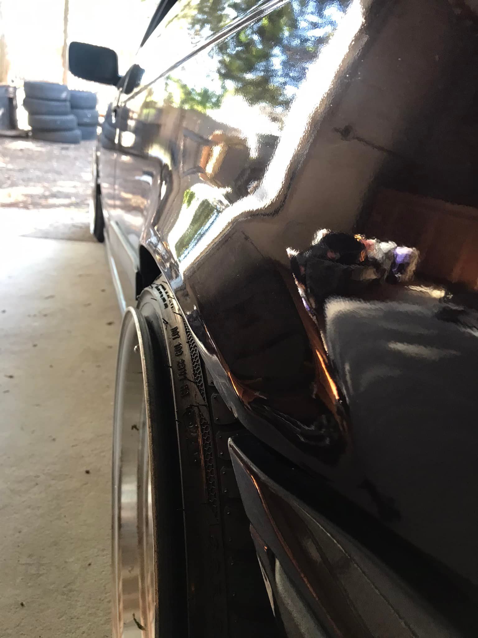 Black car with a wheel close up in garage setting.