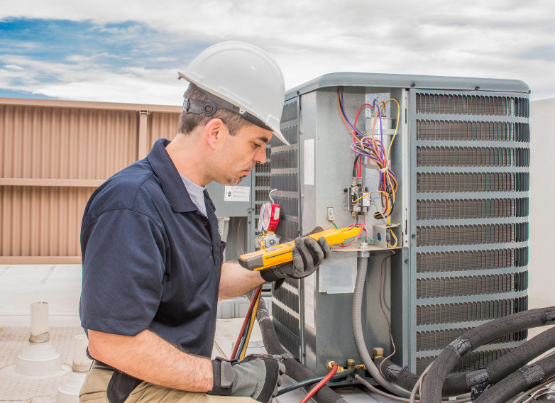 A man in a hard hat is working on an air conditioner.