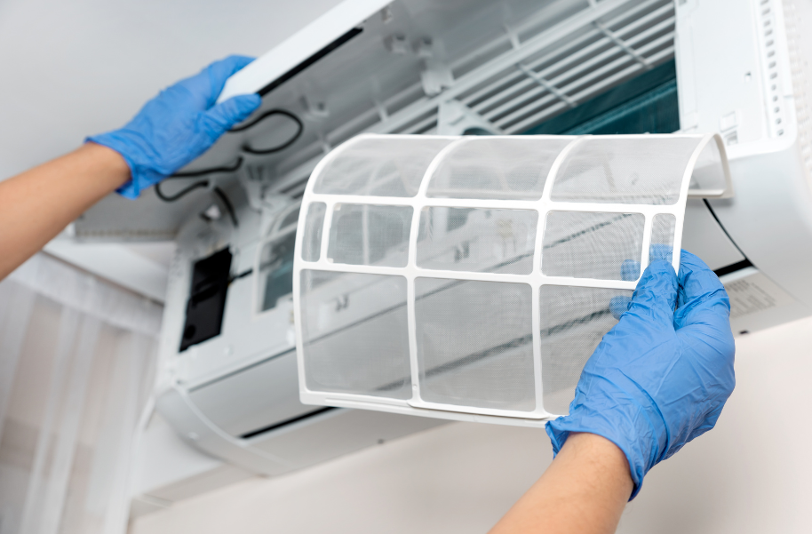 A person wearing blue gloves is cleaning an air conditioner.