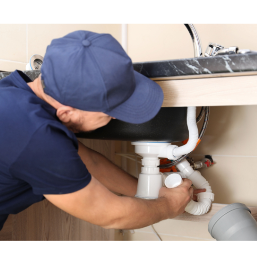 A plumber is fixing a sink in a kitchen.