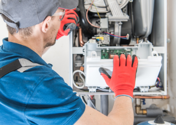 A man wearing red gloves is working on a boiler.
