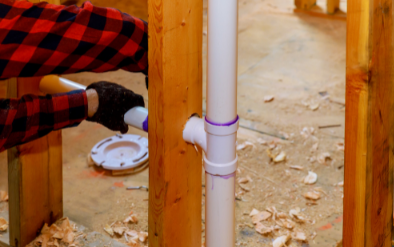 A man is installing a pipe in a wooden frame.