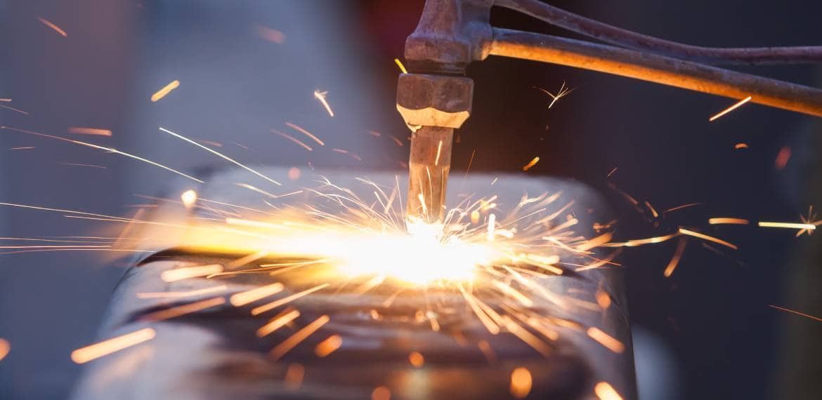 A person is welding a piece of metal with sparks coming out of it.