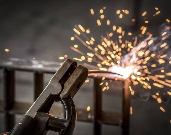 A person is welding a piece of metal with sparks coming out of it.