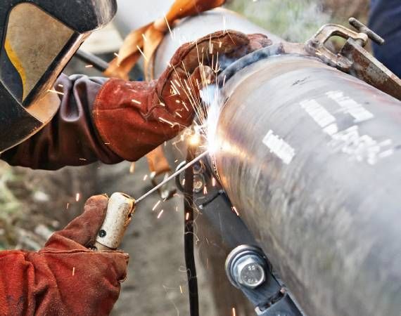 A man is welding a pipe with sparks coming out of it