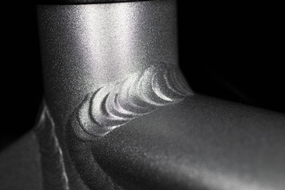A close up of a metal pipe with a welding pattern on it.
