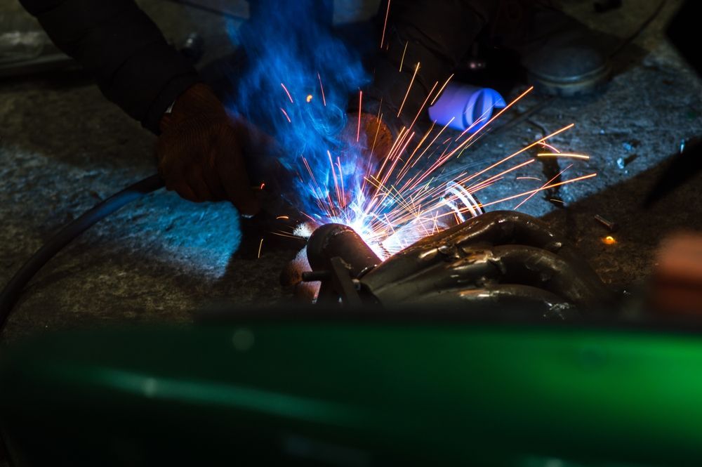A person is welding a piece of metal with sparks coming out of it.