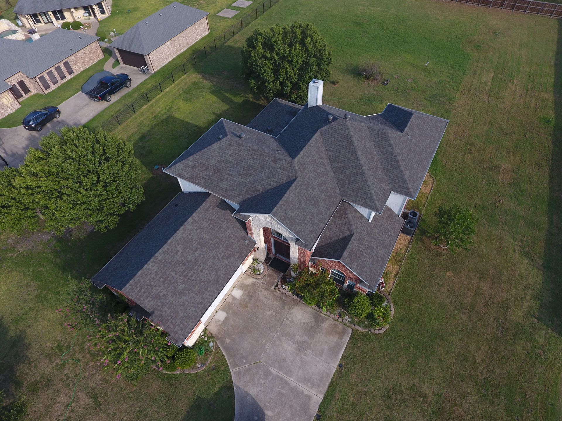 Aerial view of a gray-roofed suburban house with a driveway and surrounding lawn.