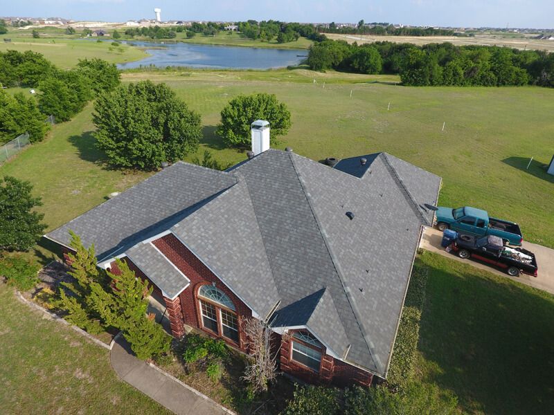 An aerial view of a house with a lake in the background