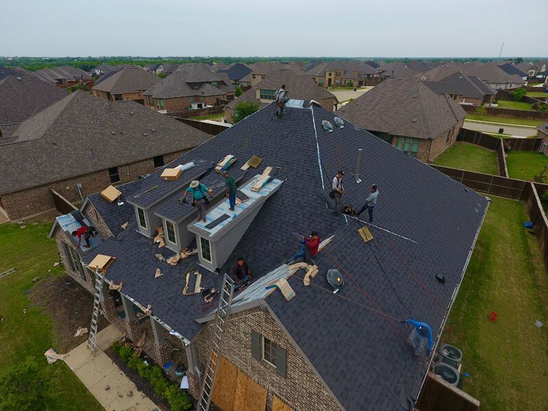 A group of people are working on the roof of a house.