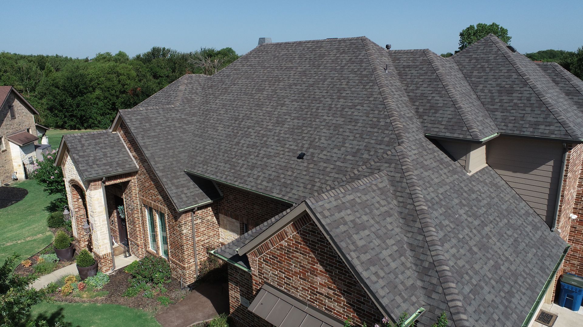 An aerial view of a large house with a pool in the backyard. An aerial view of a large house with a gray roof.