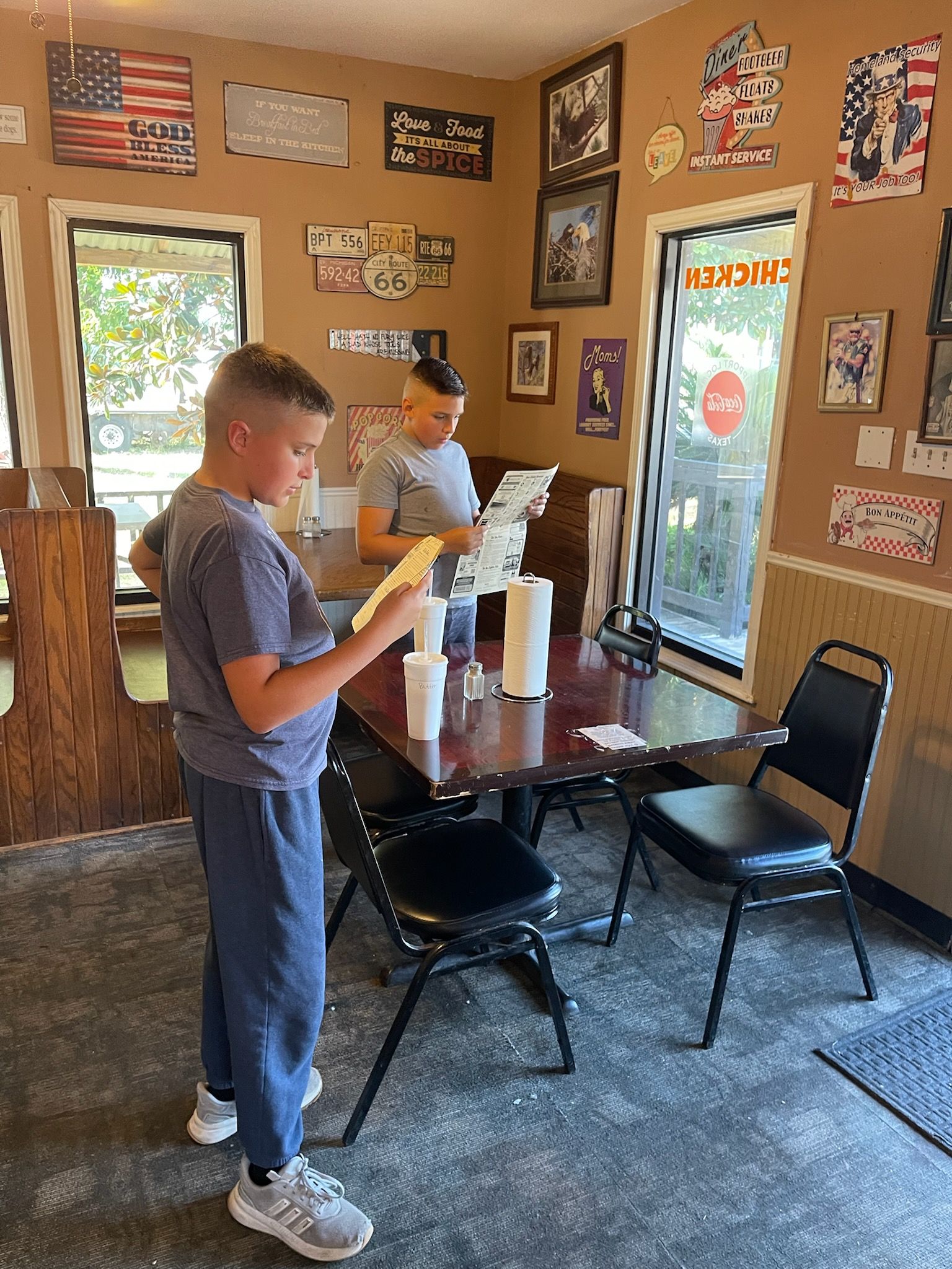 Two boys at a table, looking at papers. Restaurant interior with patriotic decor.
