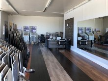 Showroom with flooring samples, desk, and large mirror.