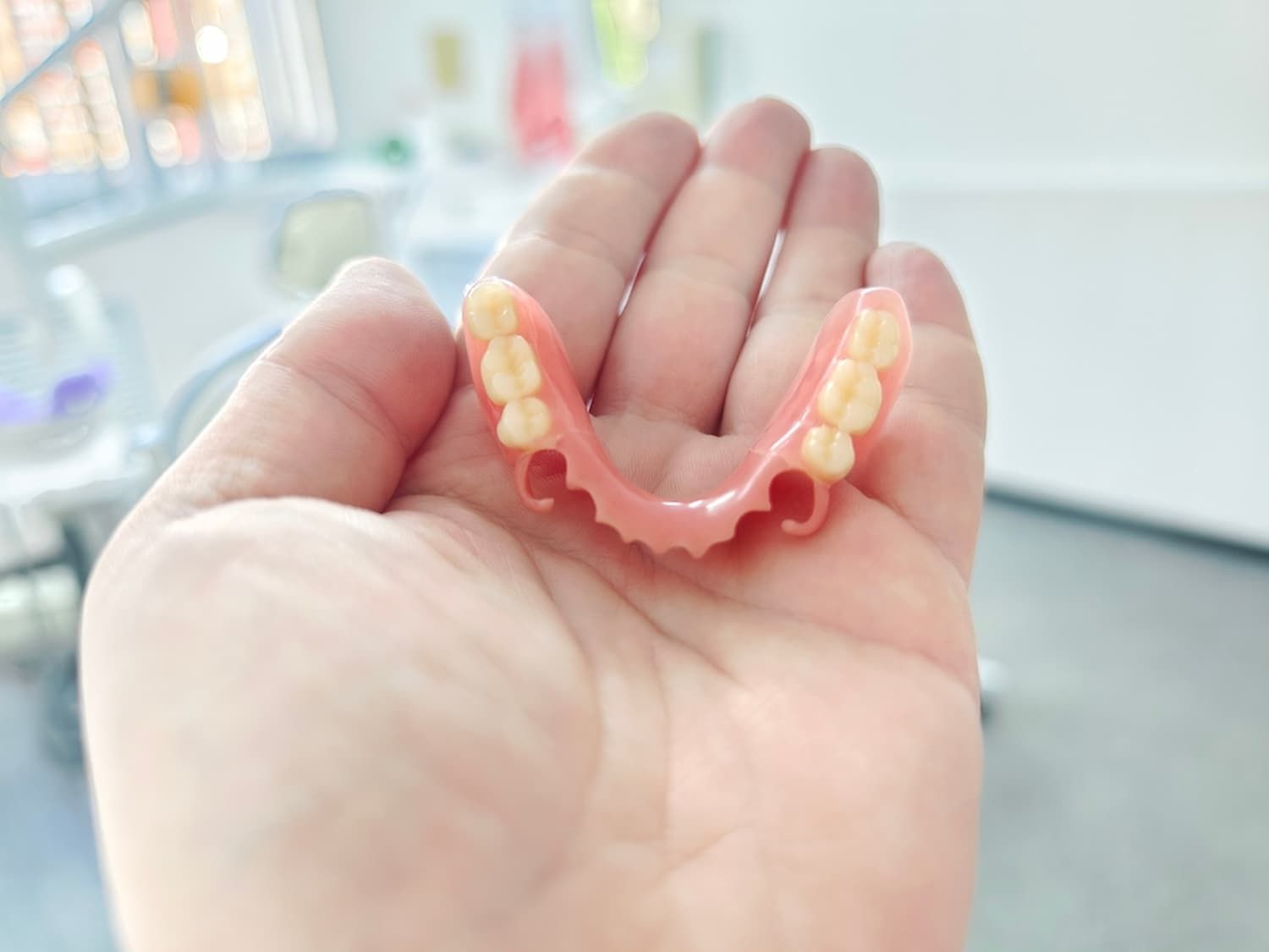 A Person Is Holding a Denture in Their Hand — Cane to Coast Dentures in Sarina, QLD
