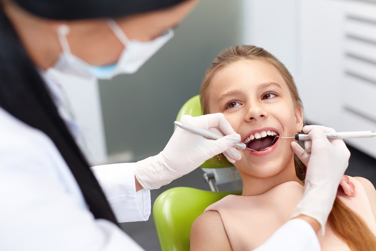 A Young Girl Is Sitting in A Dental Chair Getting Her Teeth Examined by A Dentist — Cane to Coast Dentures in Proserpine, QLD