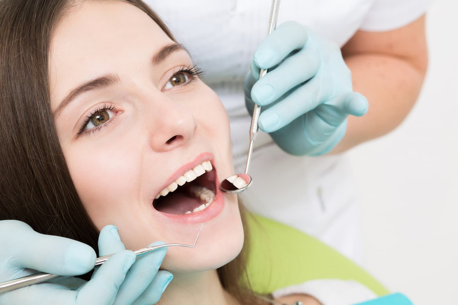 A Woman Is Getting Her Teeth Examined by A Dentist — Cane to Coast Dentures in Sarina, QLD