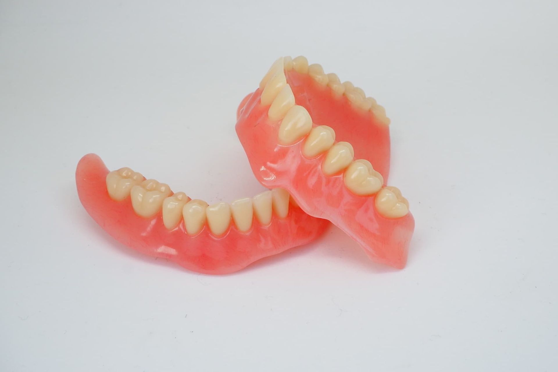 A Pair of Dentures Are Sitting on Top of Each Other on A White Surface — Cane to Coast Dentures in Sarina, QLD