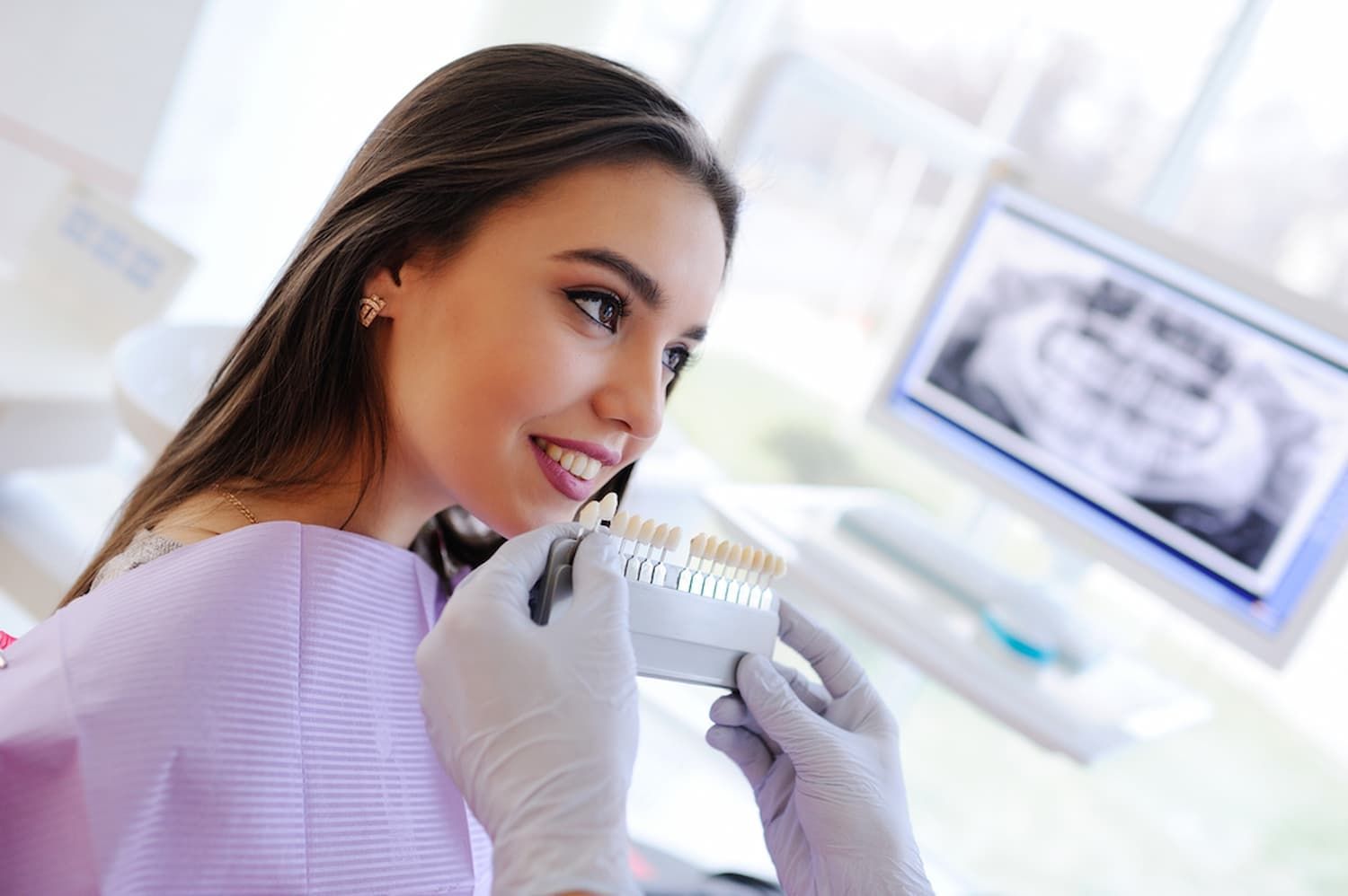A Woman Is Sitting in A Dental Chair Holding a Model of Her Teeth — Cane to Coast Dentures in Proserpine, QLD
