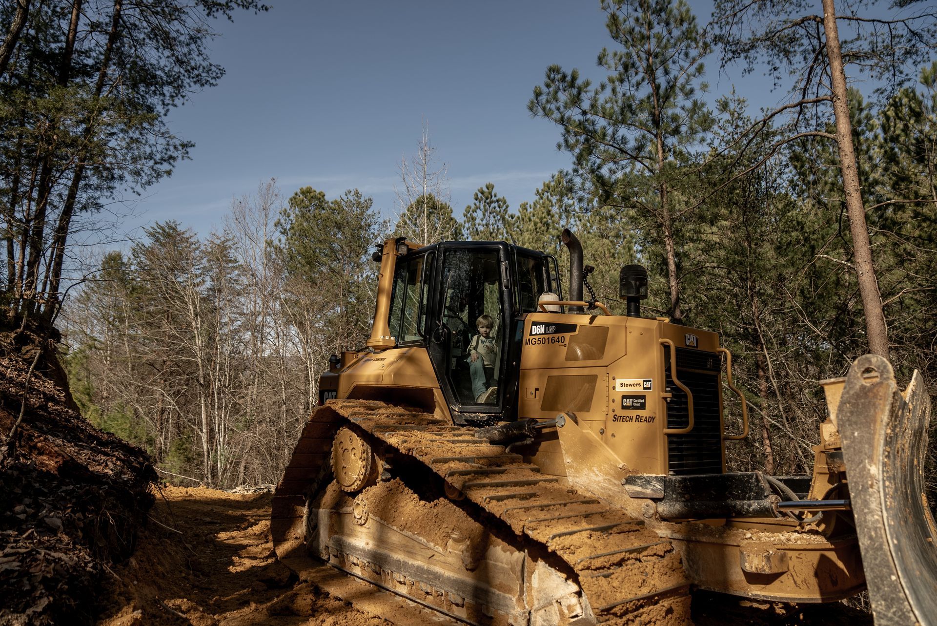 Yellow bulldozer clearing a forest path.