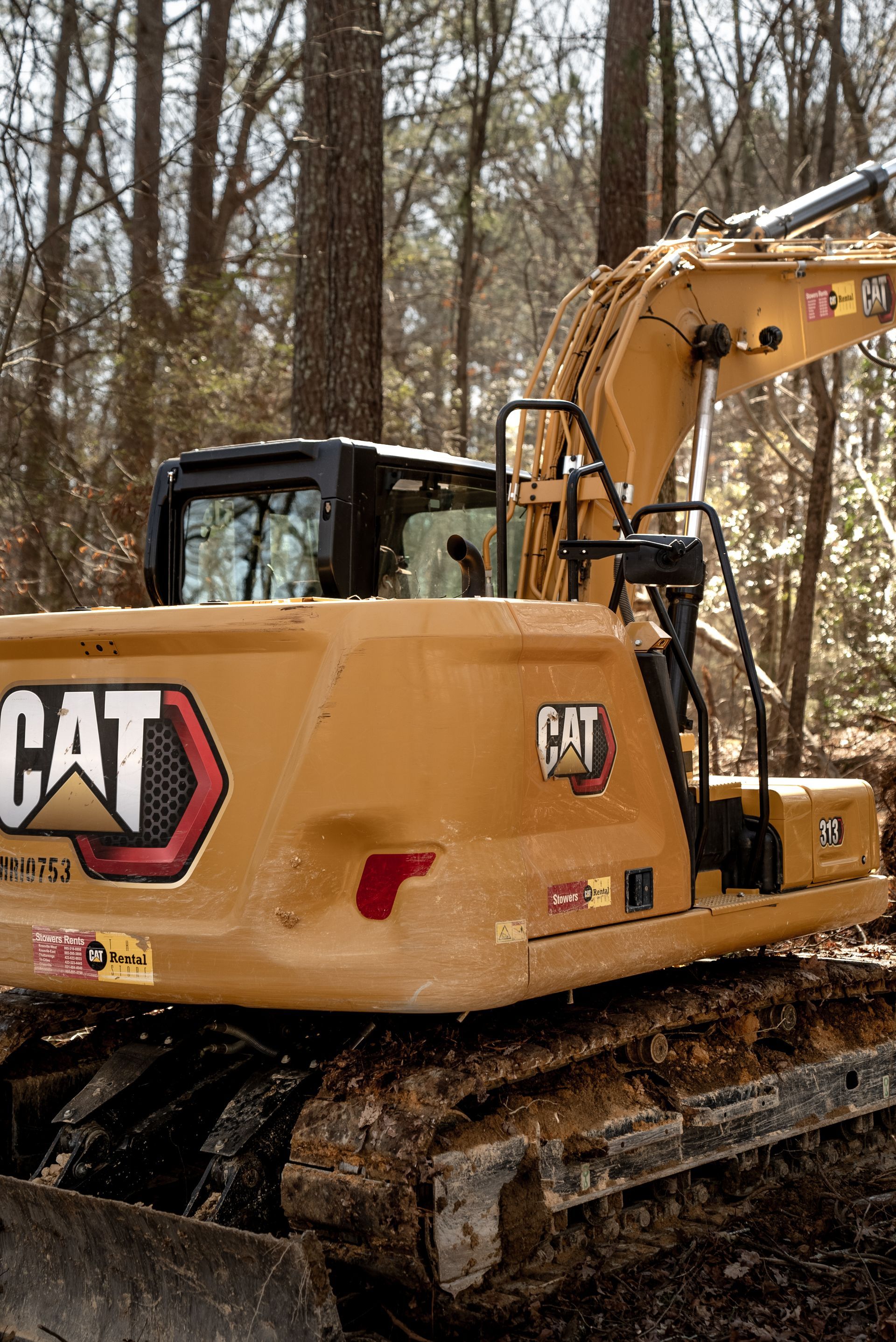 Yellow CAT excavator in a wooded area.
