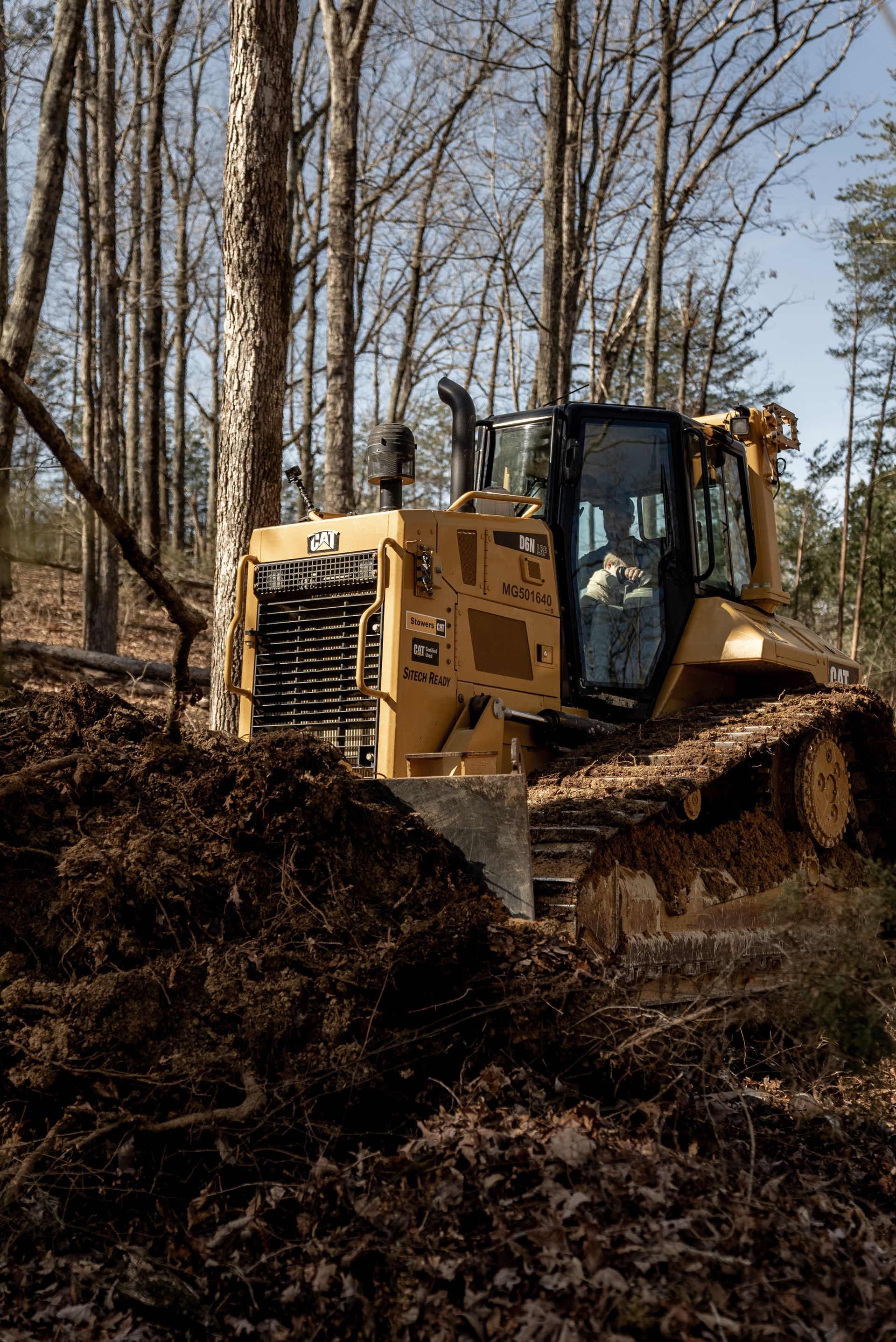 Yellow bulldozer clearing dirt in a forest.