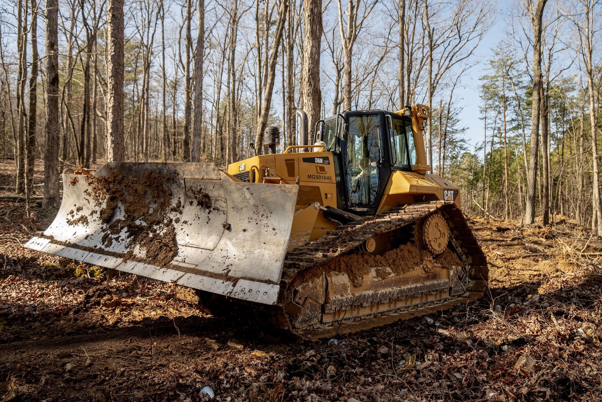 Yellow bulldozer clearing trees in a forest.