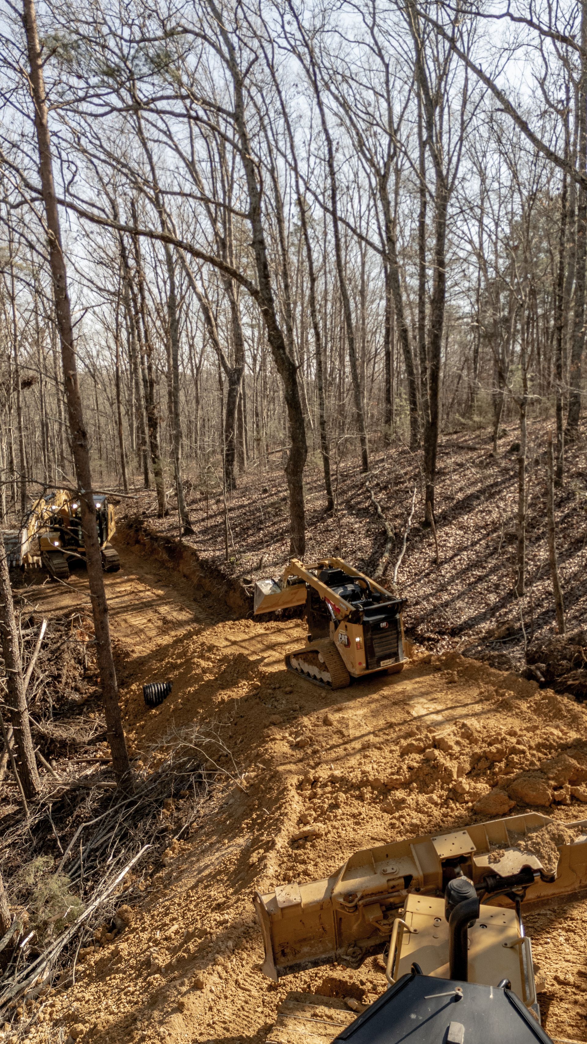 Yellow excavator loading debris into a dump truck at a construction site.