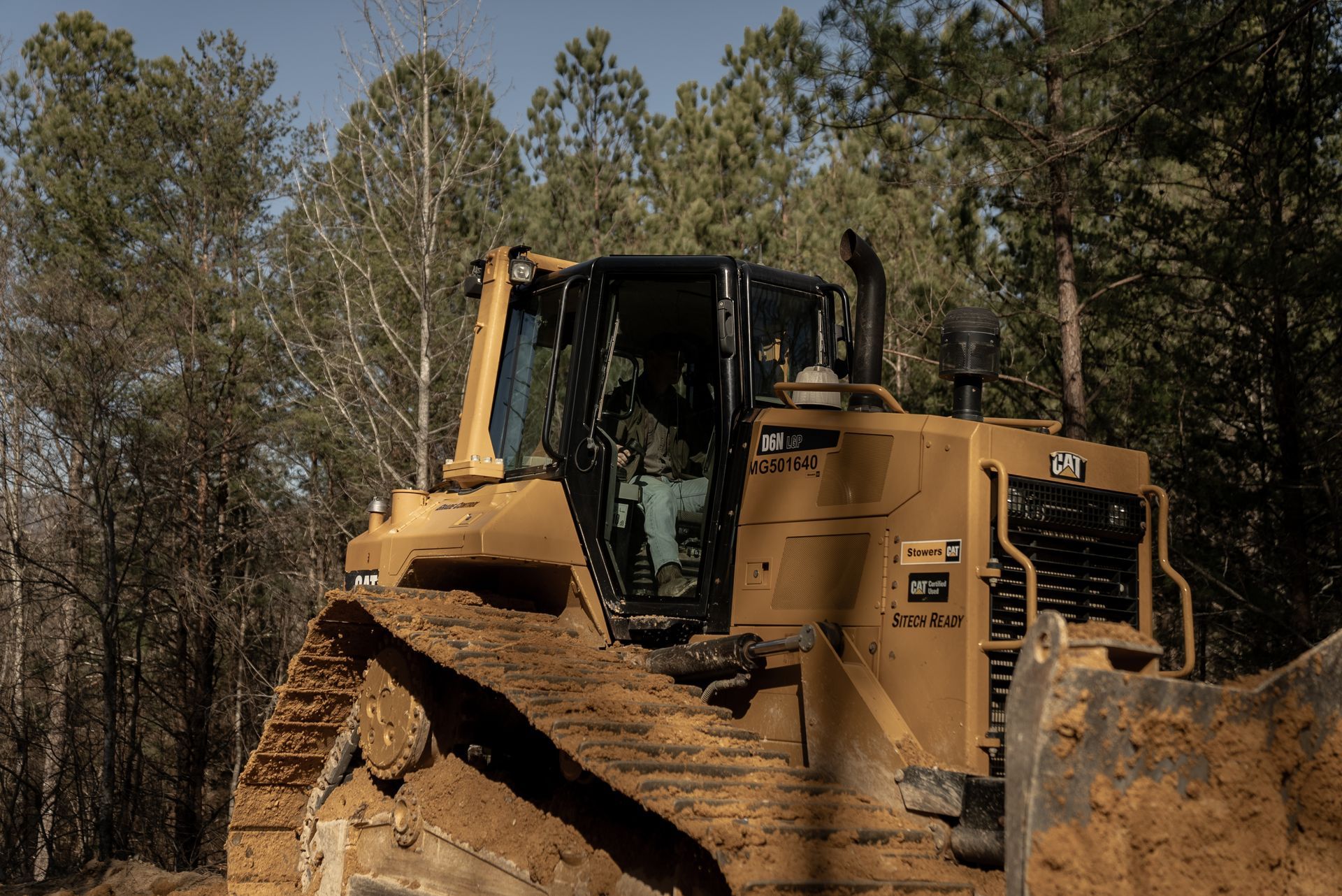Yellow bulldozer moving through a muddy forest.
