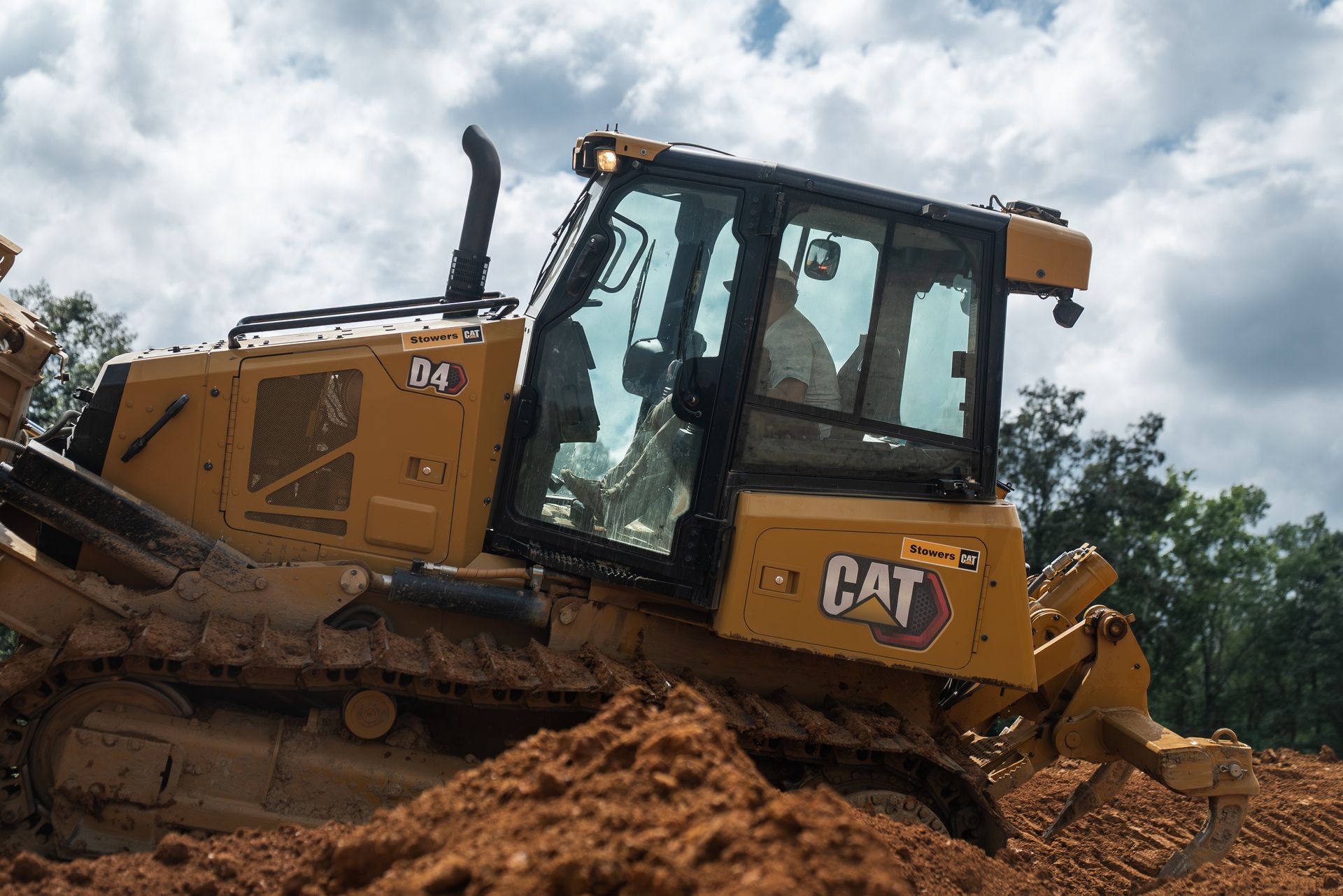 Yellow Caterpillar D4 bulldozer moving dirt on a construction site.