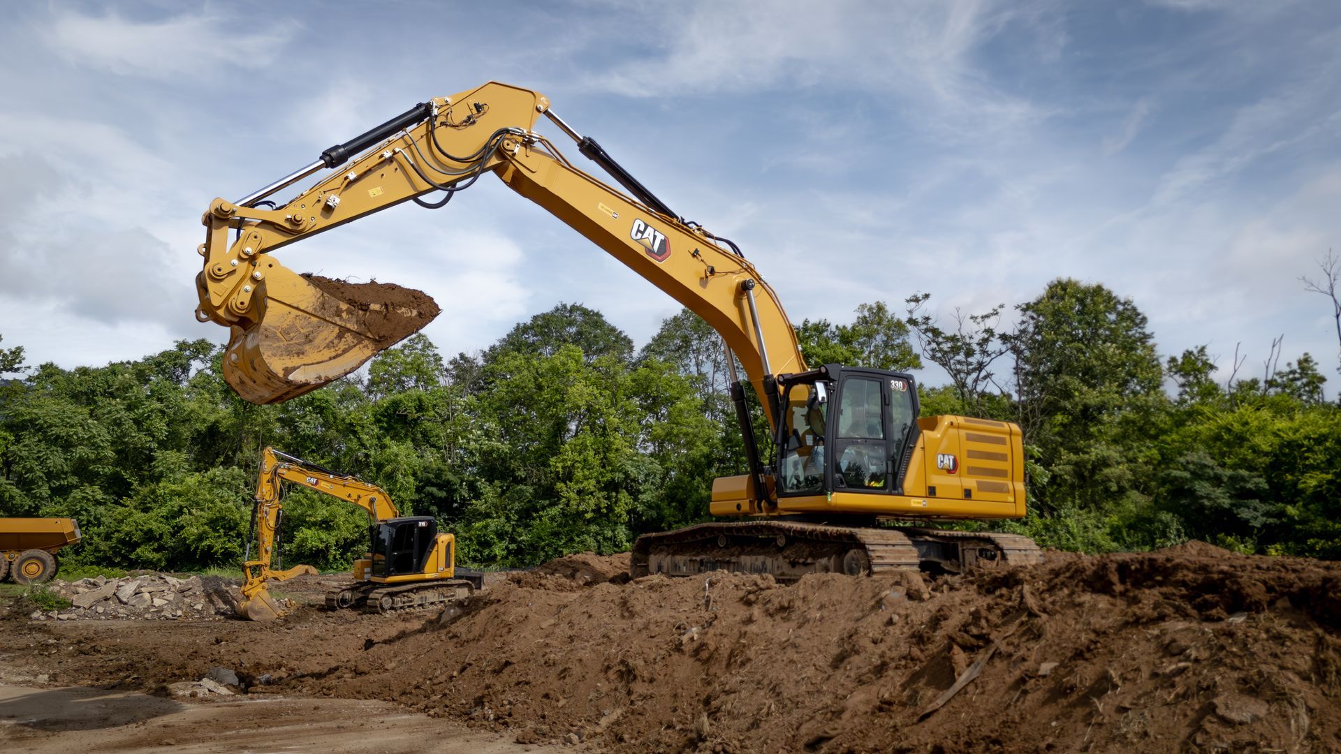 Yellow excavator digging in dirt; trees and cloudy sky in background.