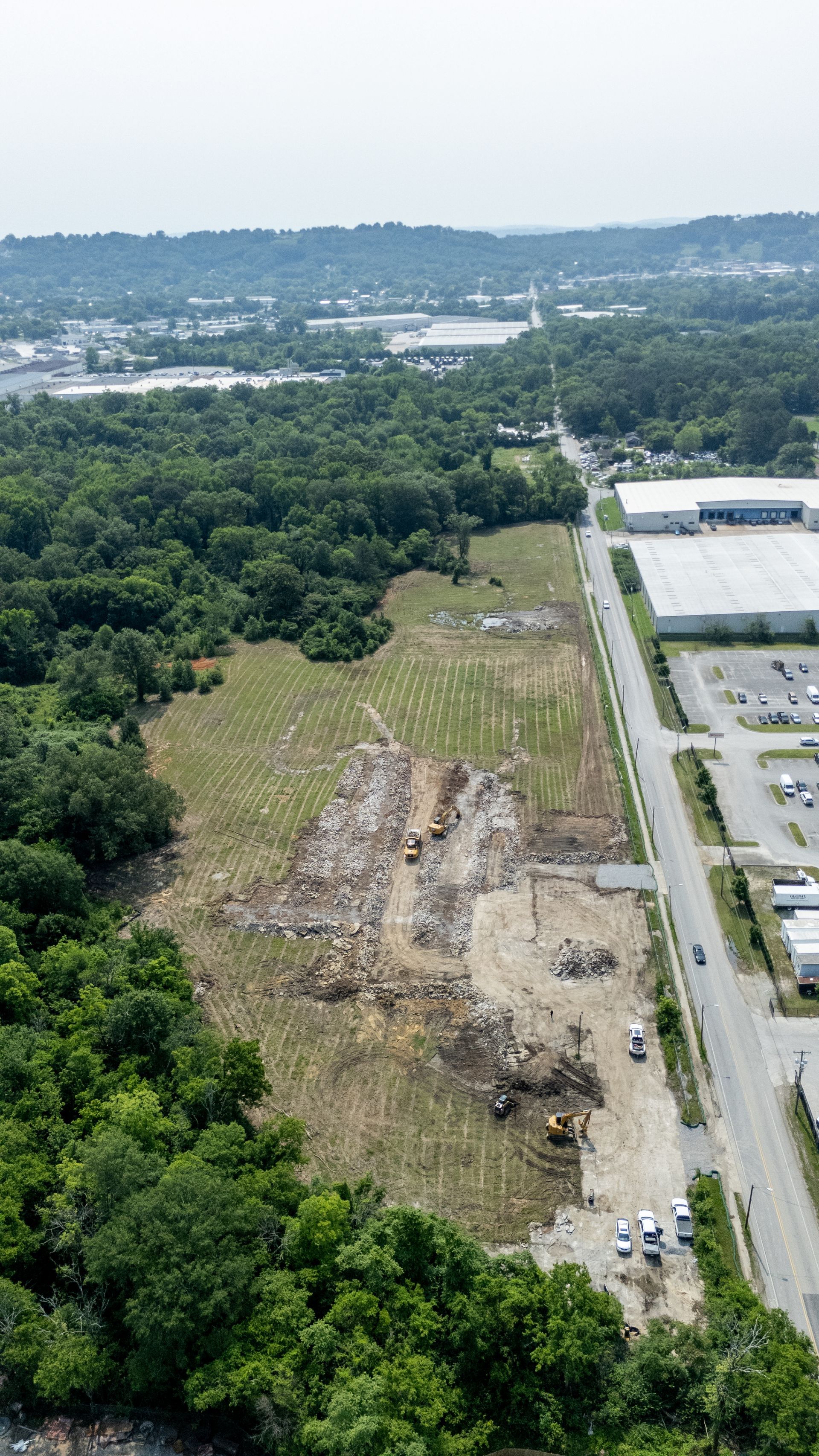 Aerial view of land clearing for construction next to a road and forest.