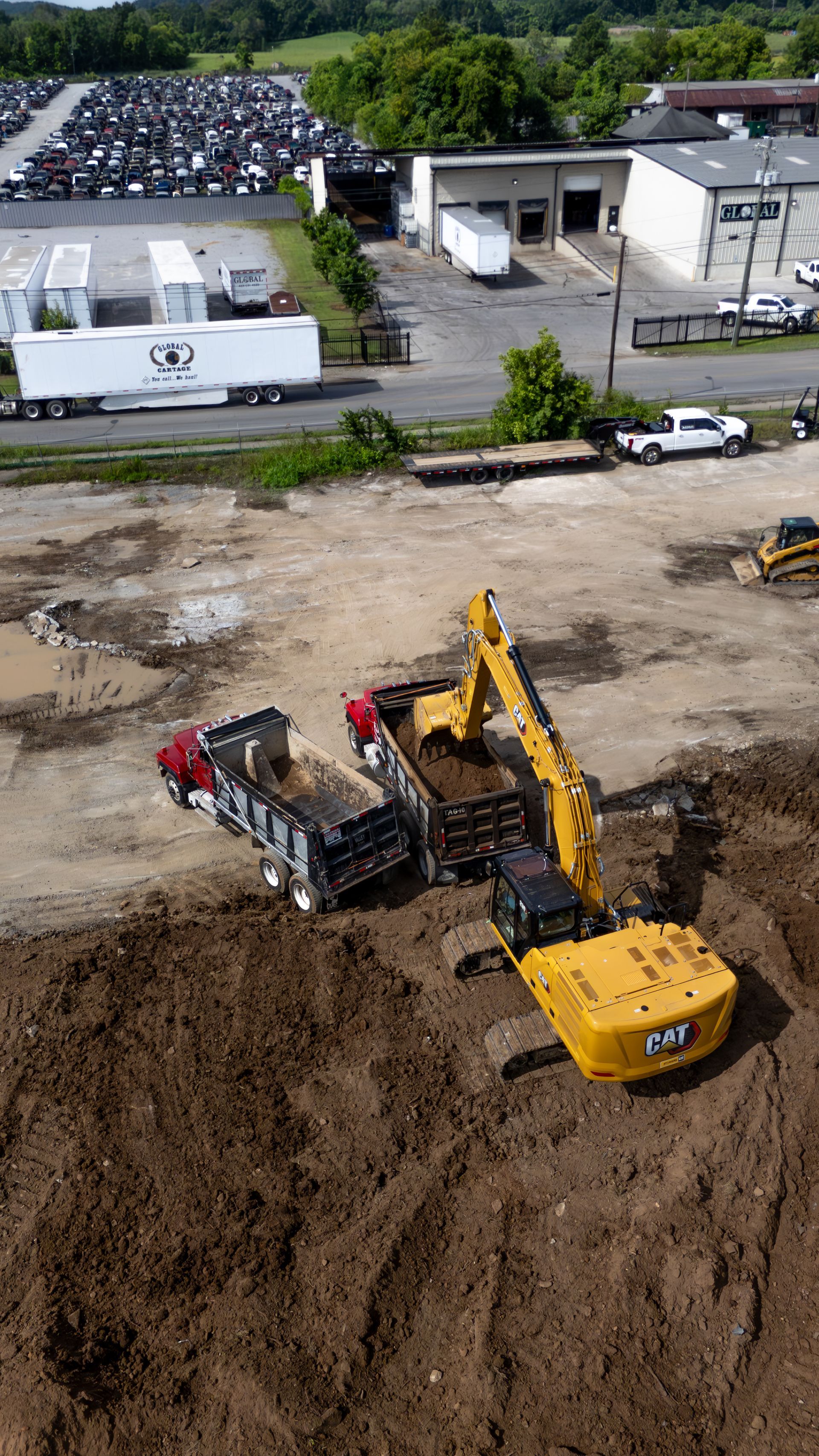Yellow excavator loading a black dump truck at a construction site.