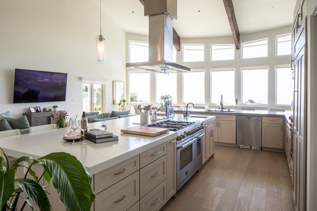 Modern, open-concept kitchen with a large white island, stainless steel appliances, and a wall of windows.