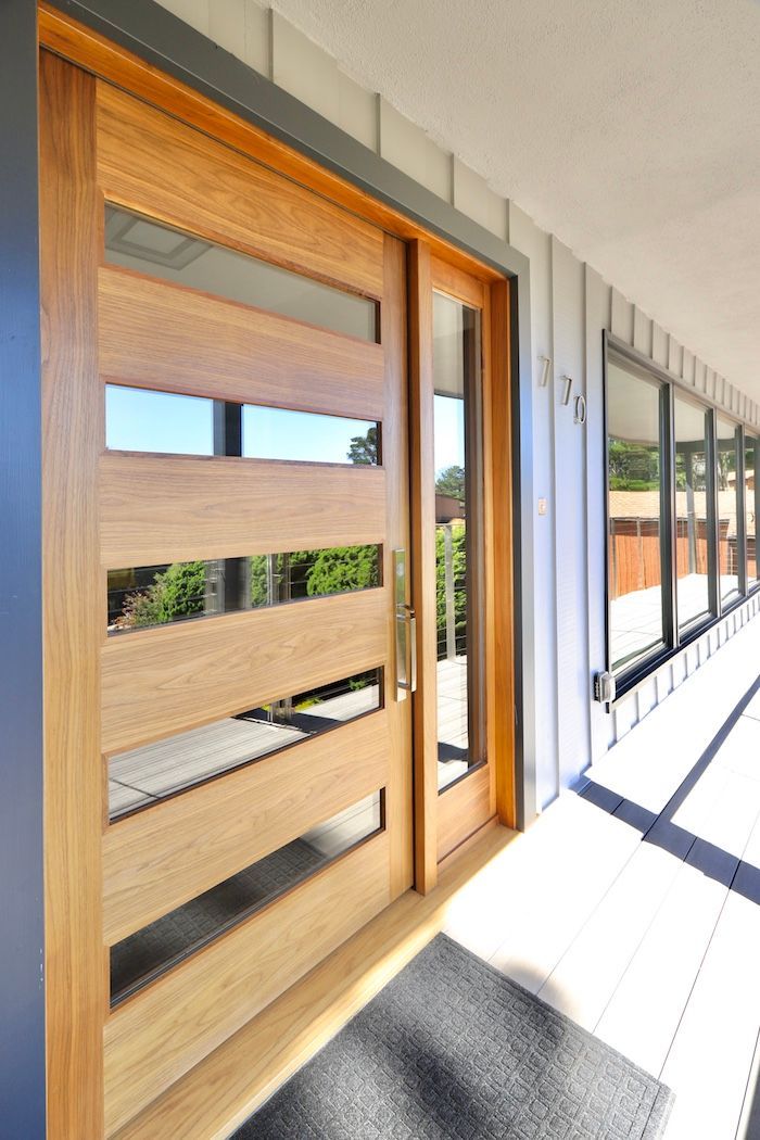 A modern, light-wood front door with five horizontal glass panels and a side light, set against a grey-paneled exterior.