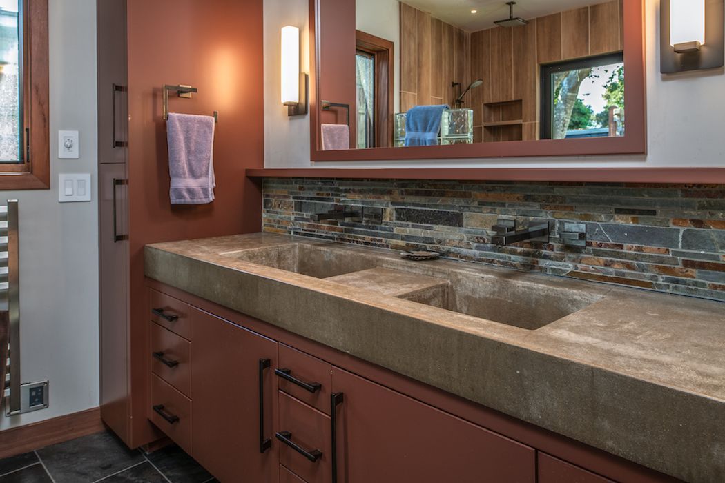 Double bathroom vanity with stone countertop, tile backsplash, and rustic red-brown cabinets.