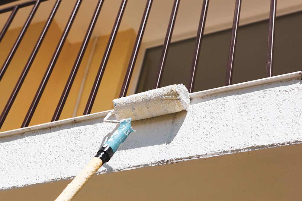 A person is painting a railing with a roller.